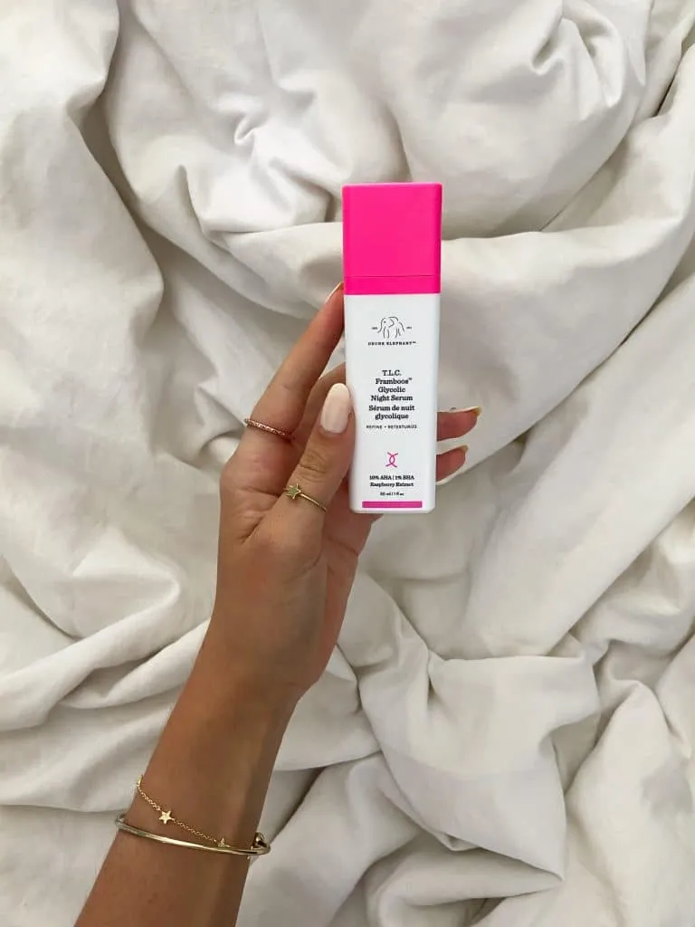 Hand holding the hot pink Drunk Elephant T.L.C. Framboos Glycolic Night Serum