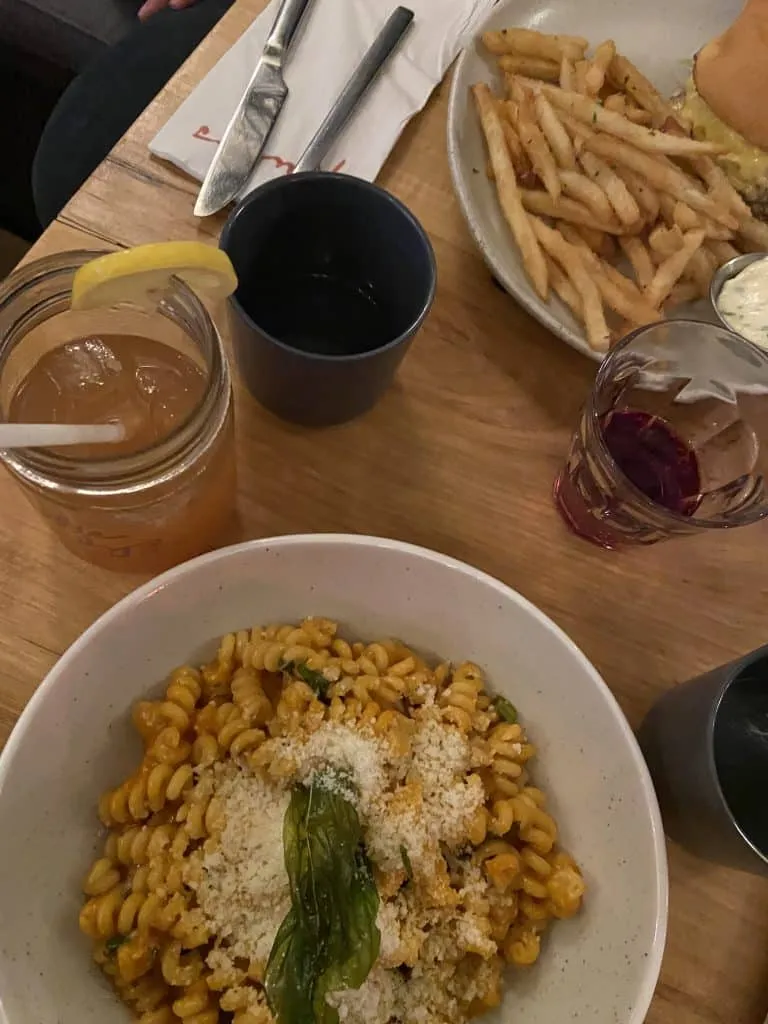 Creamy orange pasta bowl beside fries and a cheeseburger with iced tea at Ruby's