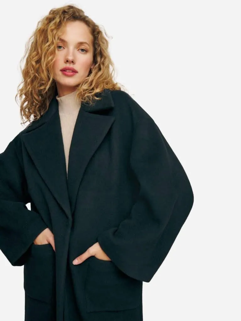 Model in a dark oversized Reformation wool coat