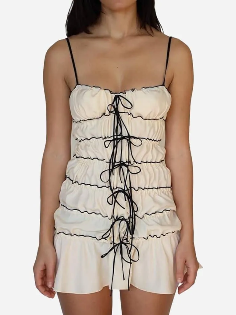 Cream ruffle tunnel mini dress with black bow ties down the front