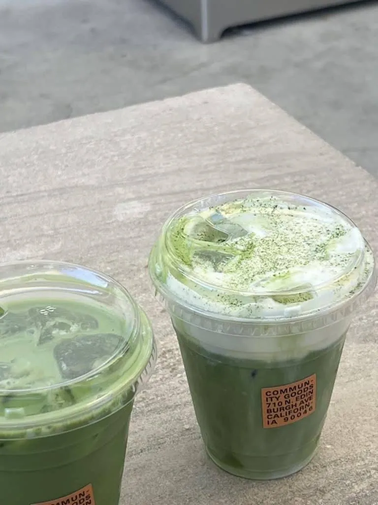 Two iced matcha lattes in plastic cups from Community Goods, one topped with cold foam dusted in matcha