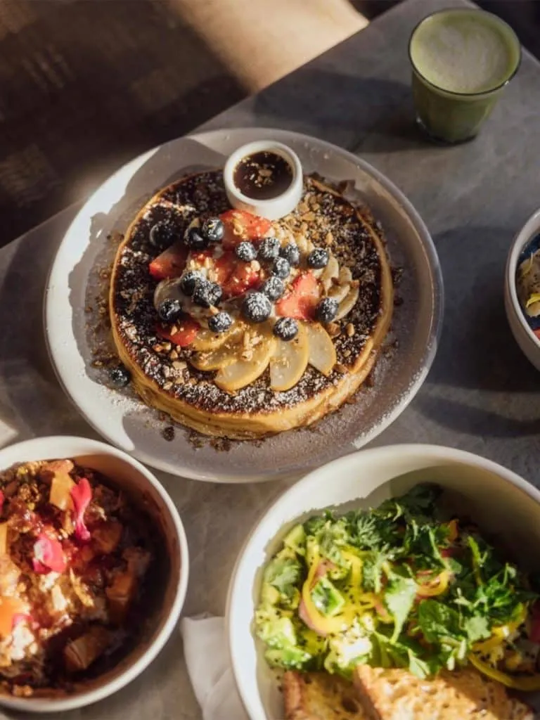 Brunch at Great White: fruit-topped pancake, green breakfast bowls, toast and a frothy green matcha drink