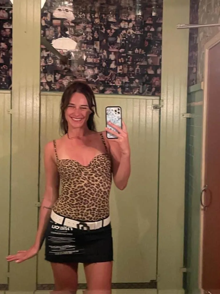 Mirror selfie in the green photo-covered bathroom at Jones, girl in a leopard top and black mini skirt