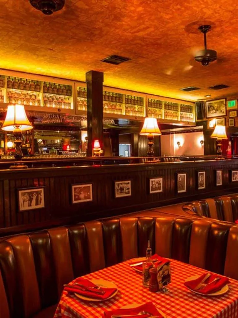 Dim Jones dining booth with tufted leather seating, a red checkered tablecloth and warm table lamps