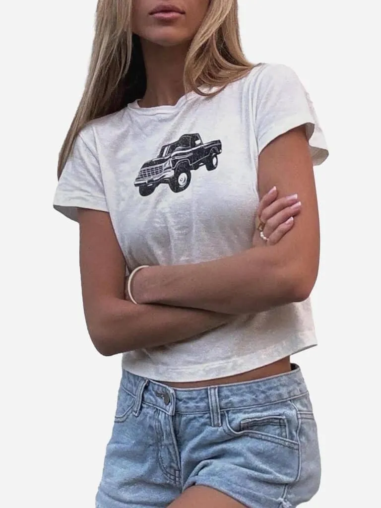 Woman in a white baby tee with a black pickup truck graphic and light denim shorts