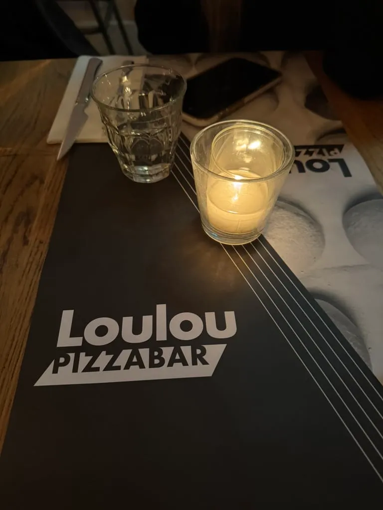 Candle and water glass on a Loulou Pizzabar placemat