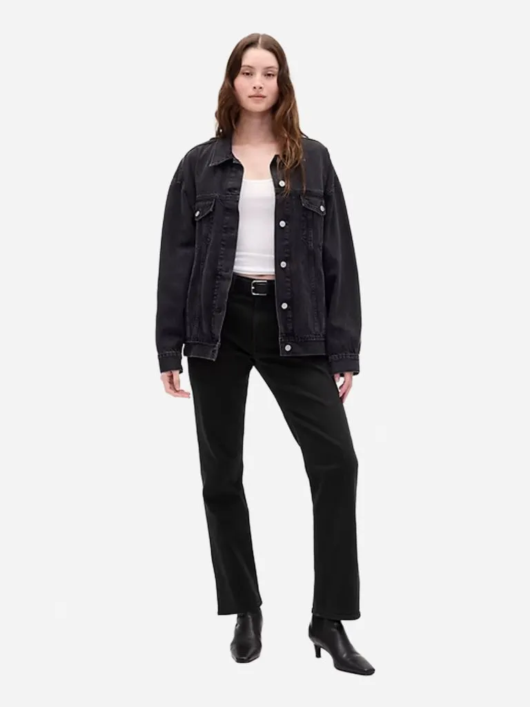 Model in black high-rise slim straight jeans with a black denim jacket, white tank and black heeled boots