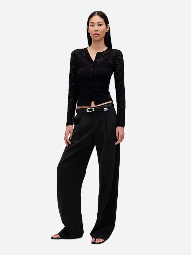 Model in a black lace cardigan with black wide-leg trousers and a silver buckle belt