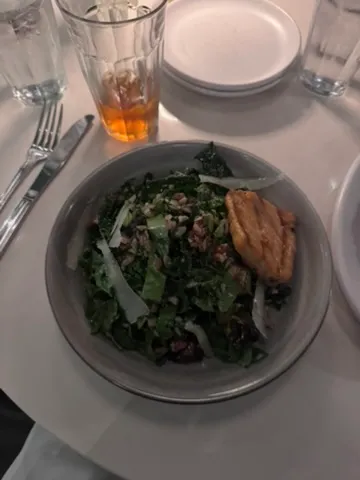 Kale salad with grains and shaved parmesan topped with a piece of salmon at The Henry in Brickell