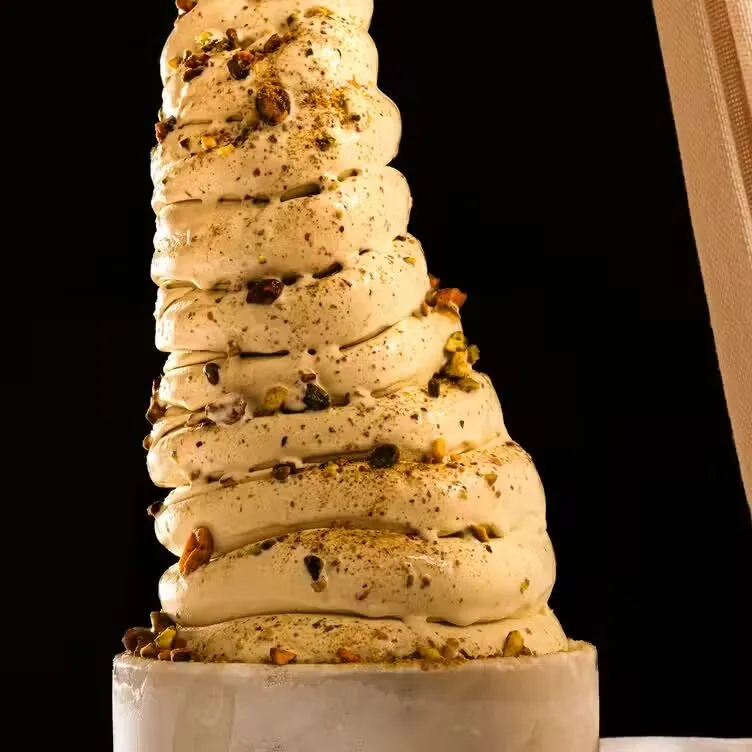 Tall swirl of pistachio gelato topped with chopped pistachios at Forte Dei Marmi